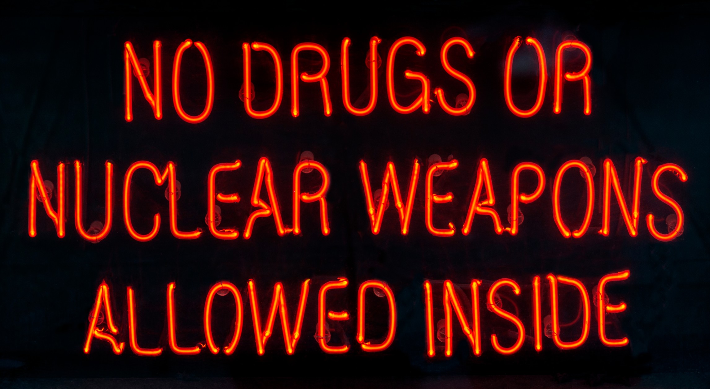 Neon sign that says, "No drugs or nuclear weapons allowed inside."